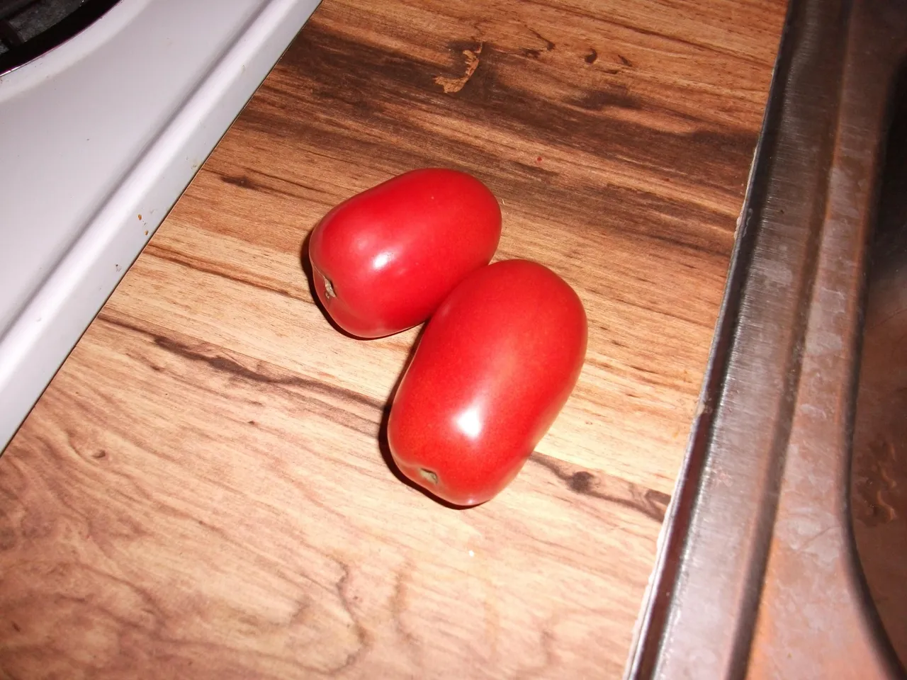 A pile of ripe Roma tomatoes, oblong and deep red.